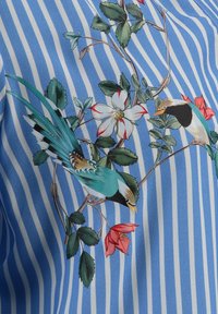 Blauw gestreepte stof met een bloem- en vogelontwerp. Opvallende elementen zijn groene bladeren, witte bloemen met rode accenten en gedetailleerde vogels.