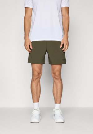 Olijfgroene shorts met een gestructureerd oppervlak, met een rechte snit en een klein zwart logo op de onderzoom. Draagt met een wit sportshirt.