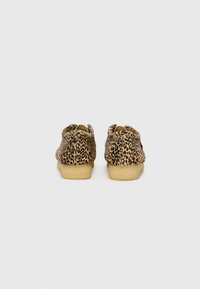 Leopard print suede shoes with a soft texture and low tan rubber sole. Rounded toe and dual openings at the back for easy wear.