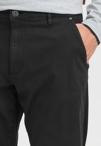 Black cotton trousers with a smooth texture, featuring a front pocket, button closure, and a straight-leg design.