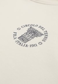 Emblème circulaire avec un dessin de colonne classique, des balles de tennis et le texte "Circolo del Tennis FTLA Italia 1911" sur fond crème.