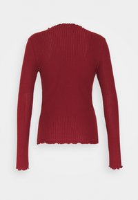 Pitkähihainen, ribbitetty punainen paita, jossa on aaltoileva kaula-aukko ja helma. Omaaa napakan siluetin ja pehmeän tekstuurin.