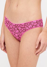 Rózsaszín virágmintás bikini alsó, sötét háttérrel, sima textúrával és kontrasztos rózsaszín díszítéssel a derékrészen.