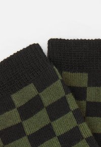 Schwarz und dunkelgrüne karierten Socken mit einem gerippten Bund und gewebter Textur, die abwechselnd feste und gemusterte Abschnitte aufweisen.
