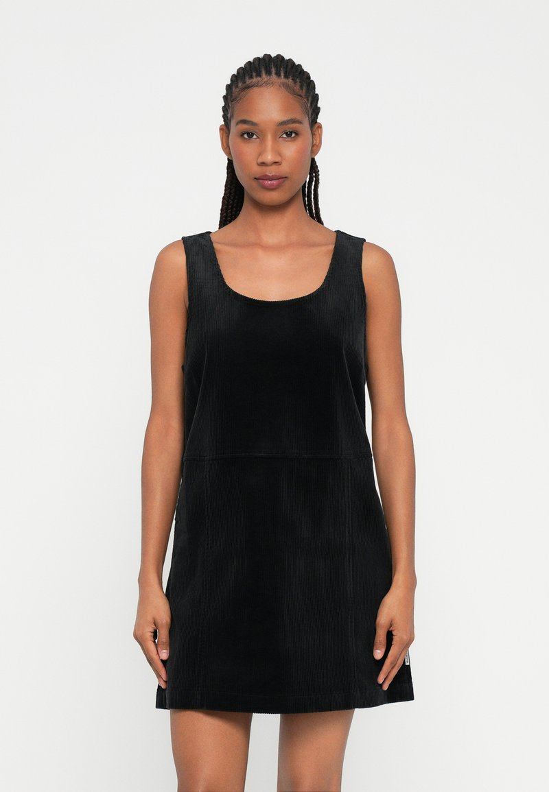 Rochie din catifea neagră cu decolteu rotund, design fără mâneci și siluetă dreaptă, având textură ribbed și detalii de cusătură minime.