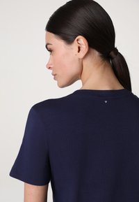 T-shirt a maniche corte blu navy in tessuto morbido, con scollatura rotonda e dettaglio discreto di un logo a forma di cuore sul retro.