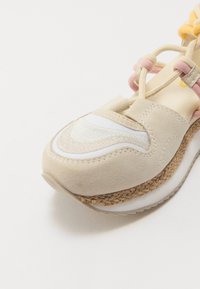 Baskets beiges avec tige en daim, accents blancs, semelle intermédiaire en jute tressé et lacets roses et jaunes. Bout rond et détails de surface texturés.
