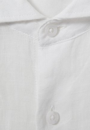Primo piano del colletto e della patta di una camicia di lino bianca con due bottoni bianchi e trama tessile visibile.