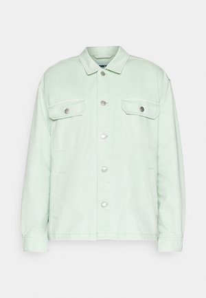Lichtgroene jack met knopen, lange mouwen, twee borstzakken met kleppen en knopen, en steekzakken aan de zijkant.