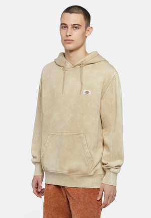 Beige cotton hoodie with a kangaroo pocket, adjustable drawstring hood, and ribbed cuffs. Features a small logo patch on the chest.