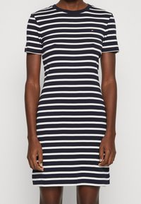 Robe rayée mettant en avant des rayures horizontales bleu marine et blanches, à manches courtes, col rond, et un design ajusté avec une texture de tissu douce.