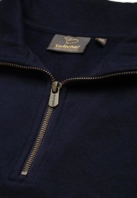 Marinefarbener Zip-Pullover mit goldfarbenem Reißverschluss und "Switcher"-Branding. Besitzt einen gerippten Kragen und eine strukturierte Stoffoberfläche.
