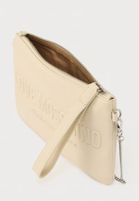 Μπεζ δερμάτινο πορτοφόλι σε στυλ clutch με ανάγλυφο κείμενο. Διαθέτει κλείσιμο με φερμουάρ, υφασμάτινη επένδυση, αποσπώμενο λουράκι καρπού και ασημένιες μεταλλικές λεπτομέρειες.