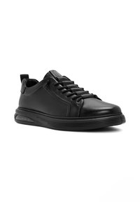 Zwarte leren sneaker met een ronde neus, vetersluiting, gevoerd kraagje en rubberen zool met een lichte hak en gestructureerde accenten.