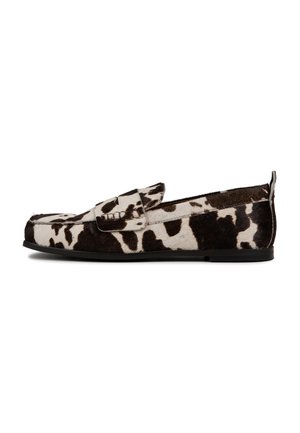 Mocasines de piel de vaca marrón y blanca con una textura suave, suela plana y una tira ancha en la parte superior. El patrón presenta manchas irregulares.