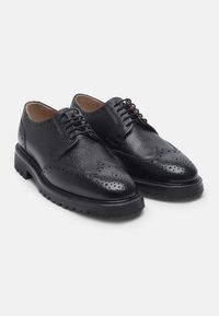 Scarpe brogue in pelle nera con finitura testurizzata, caratterizzate da dettagli perforati sulla punta, suola in gomma resistente e design tradizionale con lacci.