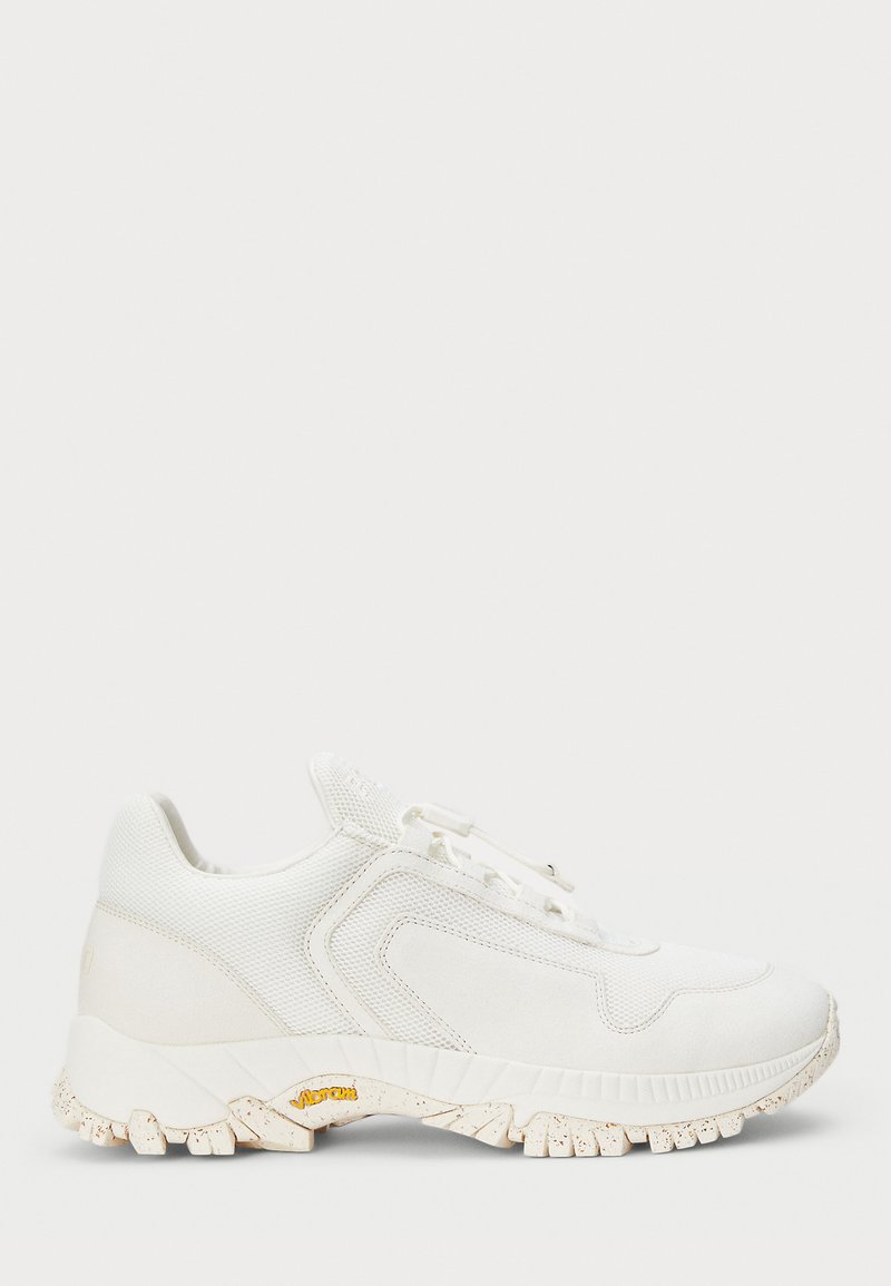 White sneaker with a mesh and suede upper, textured sole, lace-up front, and a visible logo on the heel. Features a speckled outsole.