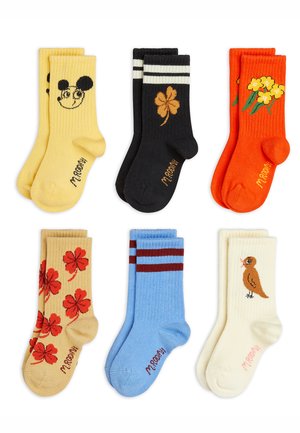 Six pairs of colorful children's socks with designs: yellow with a smiling mouse face, black with a brown clover, orange with yellow flowers, beige with red clovers, blue with red stripes, and cream with a small brown bird.