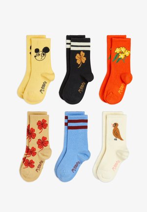 Six pairs of colorful children's socks with designs: yellow with a smiling mouse face, black with a brown clover, orange with yellow flowers, beige with red clovers, blue with red stripes, and cream with a small brown bird.