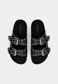 Sandales à glissière noires avec deux boucles réglables, ornées de clous argentés le long des brides ; semelle intérieure texturée pour le confort.