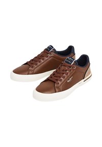 Zapatillas de cuero marrón con suela blanca, sistema de cordones intrincado y detalles en azul marino en la lengüeta y la parte trasera; cuentan con logotipo en el lateral.