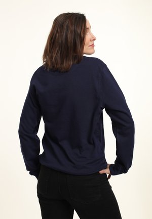 Marineblaue, langärmlige Sweatshirt mit Rundhalsausschnitt und lockerer Passform. Glatte Textur und minimale Nähdetails. Sichtbare schwarze Hosen.