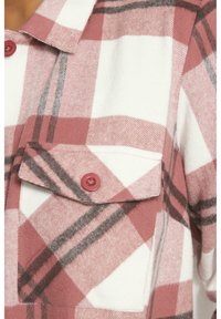 Koszula flanelowa w czerwono-białą i czarną kratę z kołnierzykiem zapinanym na guziki oraz kieszonką z przodu. Miękka w dotyku, z okrągłymi czerwonymi guzikami.