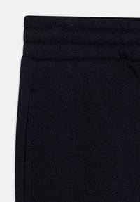 Mørkeblå bomulls joggebukser med ribbet midjebånd, elastiske mansjetter og en sidelomme. Myk tekstur uten synlige mønstre eller grafikk.