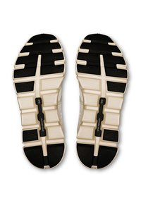 Semelles de chaussure présentant une base blanche légère avec des accents en caoutchouc noir, des motifs texturés, et un détail central en noir de type speedboard.