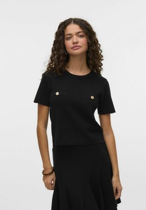 Zwarte gebreide top met korte mouwen en een aansluitend design, voorzien van twee voorzakken met gouden accenten. Zachte textuur, ronde halslijn en cropped lengte.
