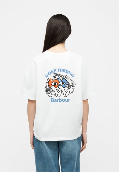 Personne aux longs cheveux foncés portant un t-shirt blanc avec des cœurs colorés dessin animé, tenant une canne à pêche et une boisson avec le texte « GONE FISHING Barbour ».