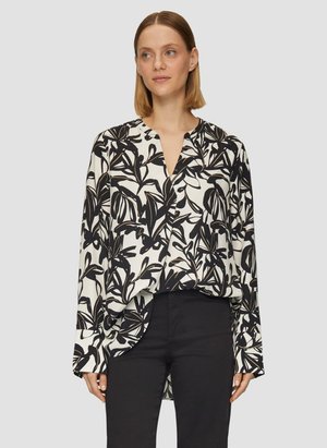 Blouse ample avec un imprimé floral noir et blanc, dotée d'un col en V, de manches longues et d'un design à ourlet asymétrique. Texture de tissu lisse.
