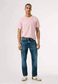 Rožinė medvilninė t-shirts, laisvas kirpimas, derinama su tamsiai mėlynomis džinsomis. Batai balti su juodais ir tamsiai mėlynais akcentais. Minimalistinis dizainas visur.