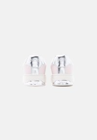 Ζευγάρι ανοιχτόροζ αθλητικά παπούτσια με μεταλλικές ασημί λεπτομέρειες στη φτέρνα και λευκές σόλες σε στρώσεις, εμφανιζόμενα από πίσω σε λευκό φόντο.