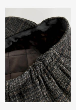 Gyapjú sapka texturált szürke-barna külsejével és szoros elasztikus pántjával a tetején. Belső része sima sötét bélésű, kockás mintával.