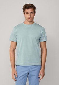 Světle modré tričko s krátkým rukávem a žebrovanou texturou, s kulatým výstřihem. V zakončení má světle modré kalhoty s rovnou siluetou.