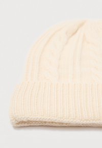 Cream-colored knitted beanie with cable patterns and a folded ribbed brim on a white background.