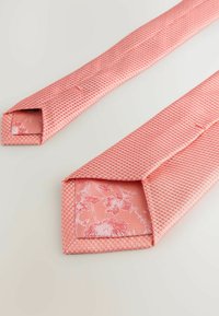 Tekstureret lyserød slips med et gittermønster. Det indre for er prydet med et blomstermønster i en lysere nuance af lyserød, med spidse ender.
