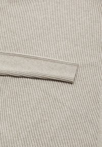 Tessuto a coste beige con una superficie morbida. Presenta un polsino largo e piatto integrato senza soluzione di continuità nel materiale, creando un aspetto uniforme.