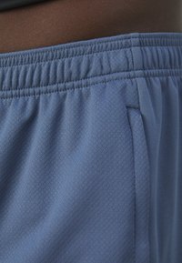 Shorts de sport bleu clair avec une finition texturée, dotés d'une taille élastique et d'une poche latérale pour plus de praticité.