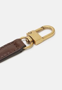 Brun læderrem med gul metalhardware, udstyret med en fjederbelastet snaphager og detaljeret syning langs kanterne.