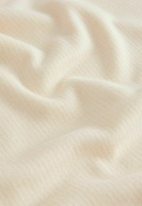 Világos bézs bordázott szövet, puha tapintással, finoman függőleges vonalakkal és lágy eséssel. Ideális ruházat vagy lakástextíliák számára.