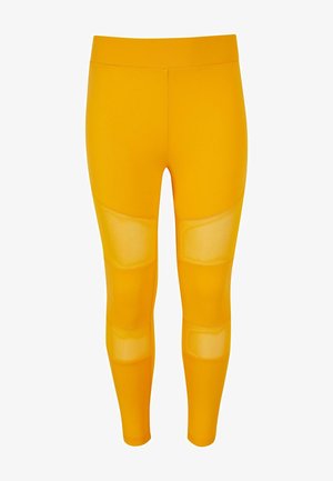Leggings jaunes en matériau extensible, dotés de panneaux en mesh transparent sur les cuisses et d'un design lisse et ajusté.