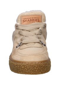 Sneaker in suede beige con suola spessa e tessuta marrone, lacci larghi, occhielli in metallo e una patch in pelle con l'etichetta "SHABBIES" sulla linguetta.
