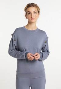 Grijze langemouwen sweatshirt gemaakt van zacht materiaal, met knoopaccenten op de schouders en een aansluitende tailleband.
