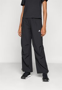 Zwarte sportoutfit met een Losse T-shirt en brede broek. De broek heeft een elastische tailleband en ritsdetails aan de zoom.