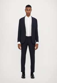 Námořnický modrý oblek s saka na jedno knoflíkové zapínání, slim-fit kalhoty a bílá košile. Hladká tkanina, minimalistický design.