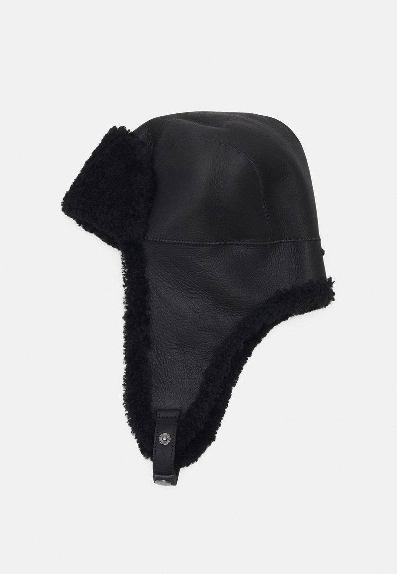 Chapeau de trappeur en cuir noir avec une doublure en shearling noir moelleux, doté de rabats d'oreilles et d'une fermeture à bouton-pression. Texture lisse avec des détails cousus.