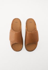 Sandali scivolati in pelle color cuoio con design a fasce incrociate e punta aperta. Interno morbido e suola testurizzata per miglior grip. Logo del marchio visibile sulla soletta.