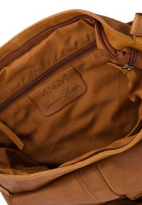 Brown leather handbag interior, featuring a smooth texture, zipper closure, and a branded leather tag reading "VENEZIA Genuine Leather."